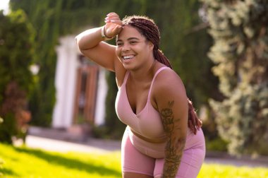 Antrenmandan sonra. Pembe spor kıyafetli genç kadın antrenmandan sonra yorgun görünüyor.