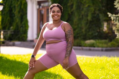 Hamleler. Pembe elbiseli bir kadın sabah antrenmanında hamleler yapıyor.