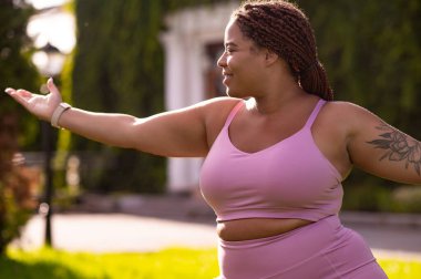 Hamleler. Pembe elbiseli bir kadın sabah antrenmanında hamleler yapıyor.