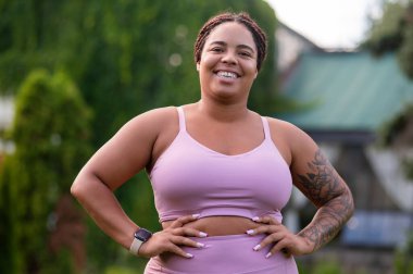 Pozitif enerji. Pembe elbiseli mutlu kadın çimlerde dikiliyor ve pozitif görünüyor.