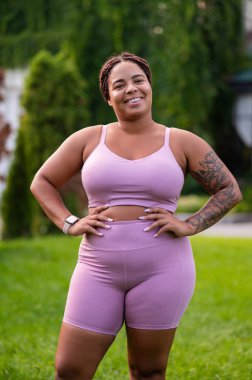 Pozitif enerji. Pembe elbiseli mutlu kadın çimlerde dikiliyor ve pozitif görünüyor.