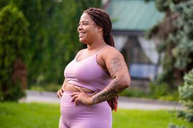 Mutlu kadın. Şirin Afro-Amerikalı pembe spor giysili genç kadın mutlu görünüyor.