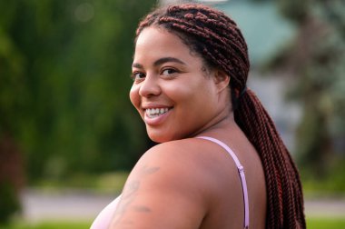 Mutlu kadın. Şirin Afro-Amerikalı pembe spor giysili genç kadın mutlu görünüyor.