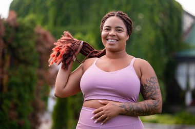 Mutlu kadın. Şirin Afro-Amerikalı pembe spor giysili genç kadın mutlu görünüyor.