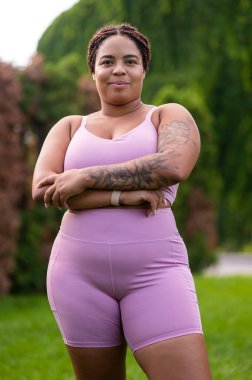 Pembe elbiseli kadın. Ayrıca kolunda pembe spor kıyafetleriyle dövmesi olan bir kadın.