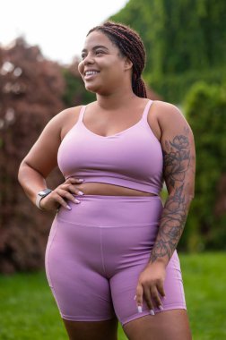 Pembe elbiseli kadın. Ayrıca kolunda pembe spor kıyafetleriyle dövmesi olan bir kadın.