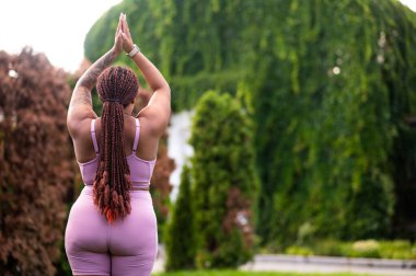 Yoga yapıyordum. Pembeli uzun saçlı kadın dışarıda yoga yapıyor ve sakin görünüyor.