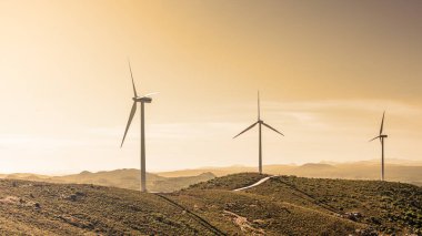Sardinya 'daki bir dağ rüzgâr çiftliğinde günbatımı ışığı olan rüzgar türbinleri. Yenilenebilir enerji konsepti, yeşil enerji üretimi. Enerji endüstrisi.