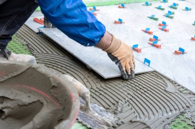 Tuğlacı tiler yeni bir zeminin fayanslarını yapıştırıcıya yerleştirir. İnşaat endüstrisi. İnşa ediliyor.