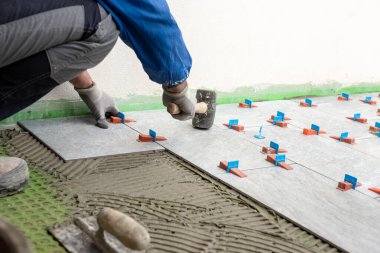 Siyah lastik çekiçli tuğla ustaları yeni bir zemin için fayanslar yerleştirdiler. İnşaat endüstrisi. İnşa ediliyor.