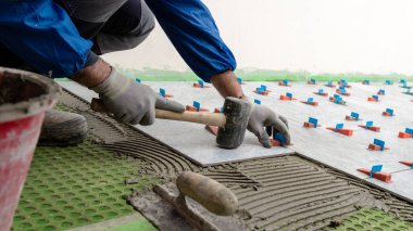 Siyah lastik çekiçli tuğla ustaları yeni bir zemin için fayanslar yerleştirdiler. İnşaat endüstrisi. İnşa ediliyor.