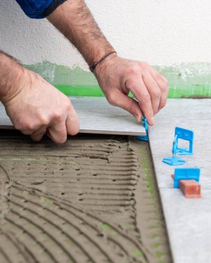 Tuğlacı tiler yeni bir zemin için çimento yapıştırıcısına fayanslar yerleştirir. İnşaat endüstrisi. İnşa ediliyor.