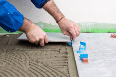 Tuğlacı tiler yeni bir zemin için çimento yapıştırıcısına fayanslar yerleştirir. İnşaat endüstrisi. İnşa ediliyor.