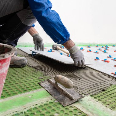 Tuğlacı tiler yeni bir zemin için çimento yapıştırıcısına fayanslar yerleştirir. İnşaat endüstrisi. İnşa ediliyor.