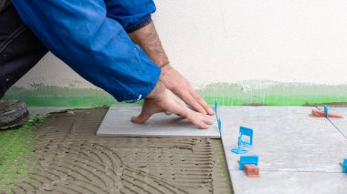 Tuğlacı tiler aralıklı seviyelendirme kullanarak fayanslar kurar. İnşaat endüstrisi. İnşa ediliyor.