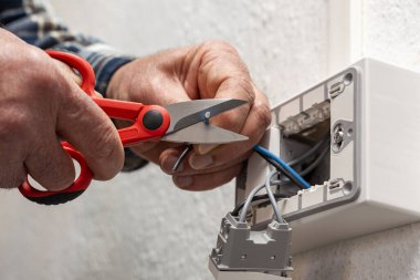 Makasla çalışan elektrik işçisi elektrik sisteminin elektrik kablolarını hazırlıyor. İnşaat endüstrisi.