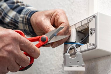 Makasla çalışan elektrik işçisi elektrik sisteminin elektrik kablolarını hazırlıyor. İnşaat endüstrisi.