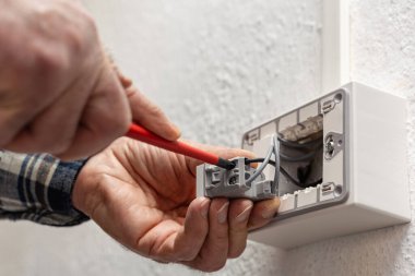 Tornavidayla çalışan elektrik işçisi elektrik sisteminin saptırıcı anahtarının terminallerindeki elektrik kablolarını tamir ediyor. İnşaat endüstrisi.