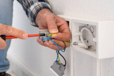 Tornavidayla çalışan elektrik işçisi elektrik sisteminin prizlerindeki elektrik kablolarını tamir ediyor. İnşaat endüstrisi.