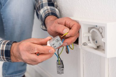 Elektrik işçisi elektrik sisteminin prizlerine elektrik kabloları yerleştiriyor. İnşaat endüstrisi.