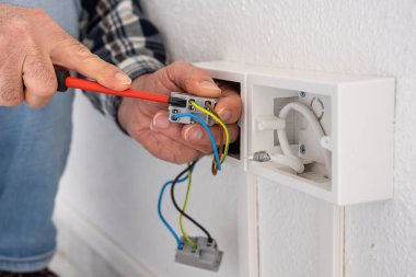 Tornavidayla çalışan elektrik işçisi elektrik sisteminin prizlerindeki elektrik kablolarını tamir ediyor. İnşaat endüstrisi.