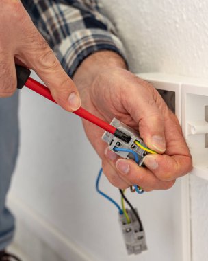 Tornavidayla çalışan elektrik işçisi elektrik sisteminin prizlerindeki elektrik kablolarını tamir ediyor. İnşaat endüstrisi.