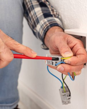 Tornavidayla çalışan elektrik işçisi elektrik sisteminin prizlerindeki elektrik kablolarını tamir ediyor. İnşaat endüstrisi.
