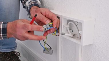 Tornavidayla çalışan elektrik işçisi elektrik sisteminin prizlerindeki elektrik kablolarını tamir ediyor. İnşaat endüstrisi. Görüntü.