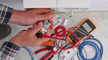 Tornavidayla çalışan elektrik işçisi elektrik sisteminin prizlerindeki elektrik kablolarını tamir ediyor. İnşaat endüstrisi. Görüntü.