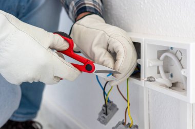 Makasla çalışan elektrik işçisi elektrik sisteminin elektrik kablolarını hazırlıyor. Koruyucu eldivenlerle güvenli bir şekilde çalışmak. İnşaat endüstrisi.