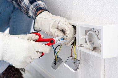 Makasla çalışan elektrik işçisi elektrik sisteminin elektrik kablolarını hazırlıyor. Koruyucu eldivenlerle güvenli bir şekilde çalışmak. İnşaat endüstrisi.