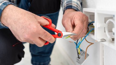 Makasla çalışan elektrik işçisi elektrik sisteminin elektrik kablolarını hazırlıyor. İnşaat endüstrisi.