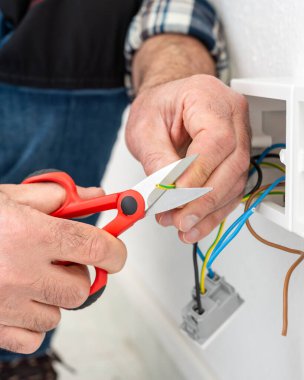 Makasla çalışan elektrik işçisi elektrik sisteminin elektrik kablolarını hazırlıyor. İnşaat endüstrisi.