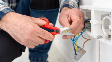 Makasla çalışan elektrik işçisi elektrik sisteminin elektrik kablolarını hazırlıyor. İnşaat endüstrisi.