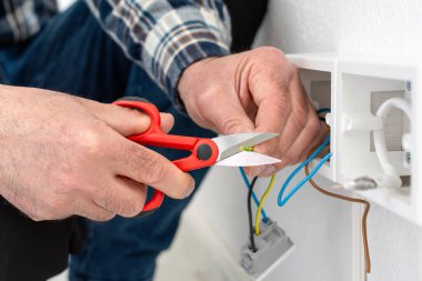 Makasla çalışan elektrik işçisi elektrik sisteminin elektrik kablolarını hazırlıyor. İnşaat endüstrisi.