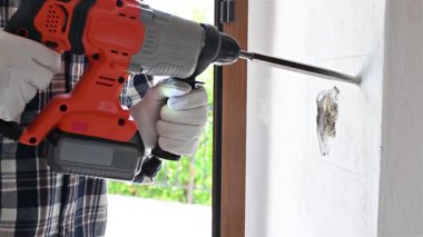 Yıkıcı çekiçli marangoz elektrikli paneli yerleştirmek için duvardaki boşluğu hazırlıyor. Koruyucu eldivenlerle dikkatli çalışın. İnşaat endüstrisi. Çekim 4k.