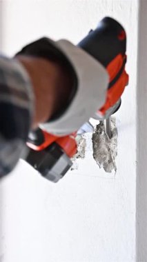 Yıkıcı çekiçli marangoz elektrikli paneli yerleştirmek için duvardaki boşluğu hazırlıyor. Koruyucu eldivenlerle dikkatli çalışın. İnşaat endüstrisi. Görüntüler yavaş çekim.