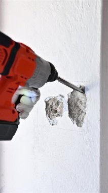 Yıkıcı çekiçli marangoz elektrikli paneli yerleştirmek için duvardaki boşluğu hazırlıyor. Koruyucu eldivenlerle dikkatli çalışın. İnşaat endüstrisi. Görüntüler yavaş çekim.