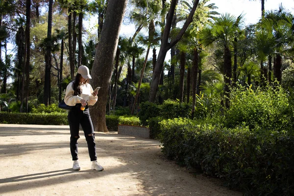 stock image woman waits in the park for her friend looking at the phone 