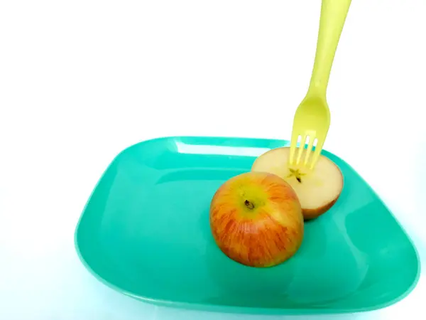 yeşil elma ve çatal beyaz tabakta