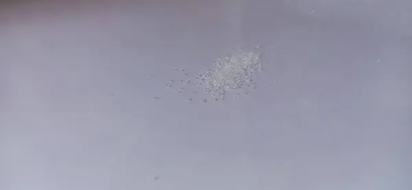 Küçük bir bardak suyla beyaz bir yüzeye yakın çekim.