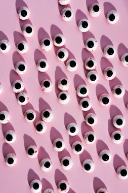 Pembe arka planda bir sürü yuvarlak plastik bebek gözü var. Düz yatıyordu. Dikey resim.