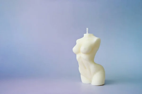 Handmade wax candle in the form of an aesthetic female body on a gray background. Background for your design with copy space.