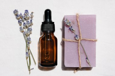 Beyaz arka planda bir demet lavanta yağı, sabun ve lavanta filizi. Yaklaş, düz yat..