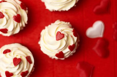 Kırmızı arka planda kalplerle süslenmiş muhallebi kekleri..