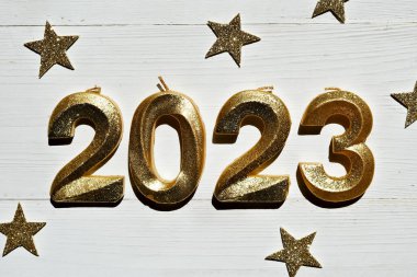 Geçmiş şenlik 2023 'ün kutlu olsun. Beyaz ahşap arka planda 2023 numaralı altın parıltı. Yan görünüm, yakın plan.