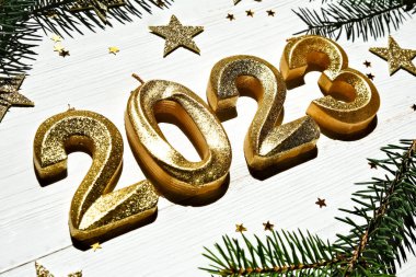Tatil geçmişi. Mutlu yıllar 2023. Beyaz ahşap arka planda, köknar dallarıyla 2023 numaralı altın parlayan numara. Yan görünüm, yakın plan.