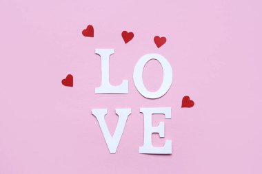 Kağıt harflerden kelime sevgisi ve pembe arka planda kırmızı kalpler. Düz yatış, mesaj için yer. Sevgililer Günü geçmişi.