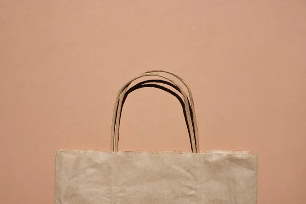 Kraft paper shopping bag on beige background. Flat stacking, space for text.