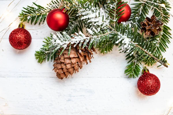 Noel kompozisyonu. Noel ağacı dalı ve beyaz ahşap arka planda Noel süslemeleri. Yan görünüm, metin için boşluk.